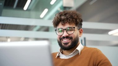 İş yerindeki bir dizüstü bilgisayarda çalışan gülümseyen iş adamı. Bilgisayarda yazan mutlu işçi, müşteriyle mesajlaşan, bir işle meşgul olan, internette sohbet eden ya da bir projeyle meşgul olan. Kapat.