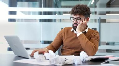 Çok çalışan işadamı dizüstü bilgisayarla çalışmaktan ve iş yerindeki çalışma masasında oturmaktan yoruldu. Yorgun bir adam iş yapmaktan sıkılır. İşçi son teslim tarihi projesiyle meşgul.