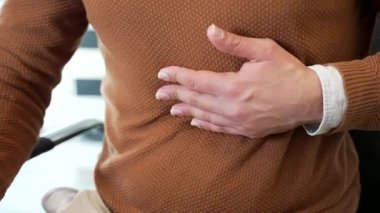 Kapatın. Günlük kazak giyen sağlıksız işadamı iş yerinde mide ağrısını hisseder. Erkek el, karın masajı yapıyor. Sağlıksız bir adam mide iltihabından ya da mide yanmasından muzdarip.