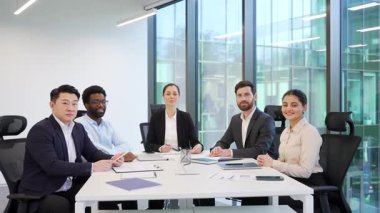 Resmi olarak çok ırklı mutlu iş adamlarının portresi yönetim kurulunda kameraya bakarak oturuyor. Başarılı gülümseyen iş arkadaşlarının iş toplantısı. Takım artı profesyonelleri