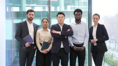 Kendine güvenen iş adamlarının resmi portresi modern cam ofiste ayakta duruyor. Bir grup ciddi iş arkadaşı kameraya bakarak poz veriyor. Profesyonel liderlerin takım çalışması