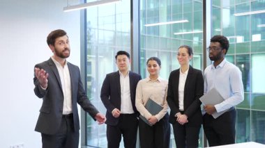 Takım elbiseli bir yönetici modern ofiste duran takım iş adamlarına katılmaya davet ediyor kameraya gülümserken bakın. İşveren, insan kaynakları girişimcisi, yatırım yapmak ya da kiralamak için arıyor. Ekip elemanlarına katılın.