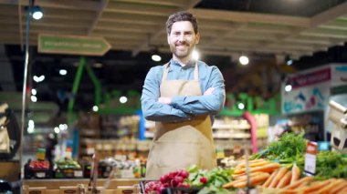 Önlüklü bir portre satıcısı markette ya da markette elinde sebzelerle kameraya bakıyor. Süpermarkette çalışan bir erkek manav ya da küçük işletme sahibi Profesyonel Personel 'de gülümsüyor