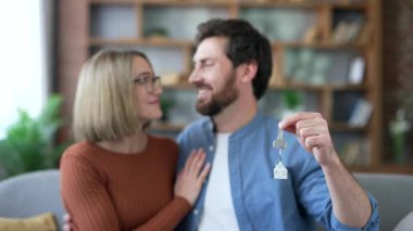 Yeni dairenin mutlu evli çiftleri kameraya bakarak yeni evin anahtarını gösteriyor. Gülümseyen eş ve koca kucaklaşır ve gülümser, oturma odasındaki kanepede oturup yeni evlerinde eğlenirler. Kapat.