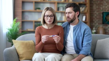Üzgün evli çift, oturma odasındaki kanepede otururken hamilelik testi yapıyorlar. Hayal kırıklığına uğramış karı koca tatminsiz ve depresif hayal kırıklığı.