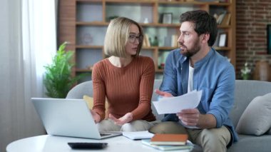 Mutsuz, evli bir çift, büyük faturalara bakıyor ve ev ofisinde oturuyor. Aile hayal kırıklığına uğramış, ev işlerinde zorlanıyor, ödeme çekleri tutuyor, dizüstü bilgisayar kullanıyor.