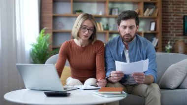 Düşünceli aile çifti ev ofisinde otururken bütçeyi ve ev giderlerini takip ediyor. Karı koca para tasarruflarını hesaplıyor, internette faturaları ödüyor.