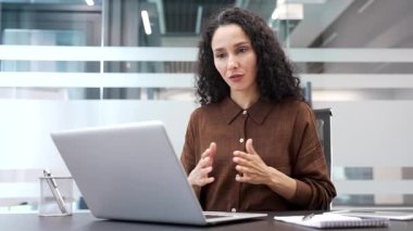 Kendine güveni tam bir iş kadını, iş yerinde otururken bilgisayar kullanarak video konferansında konuşuyor. Kadın antrenör veya öğretmen çevrimiçi eğitim, danışma, kurs veya webinar