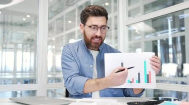 Webcam görüntüsü. Öfkeli iş adamı tartışarak video konferansında konuşuyor ve ofisteki kameraya bakıyor. Tatminsiz patron, çevrimiçi bir toplantıda grafikte kötü gösterge verilerini göstererek astlarını azarlıyor