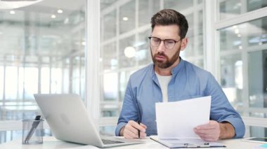 Kafası karışmış işadamı iş yerinde otururken evrak işlerinde zorlanıyor. Belgeleri incelerken ve laptop ekranına bakarken mali sonuçlardan memnun olmayan hayal kırıklığına uğramış finansör.