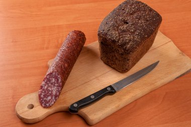 Ahşap bir masa üzerinde bıçakla dilimlenmiş sosis