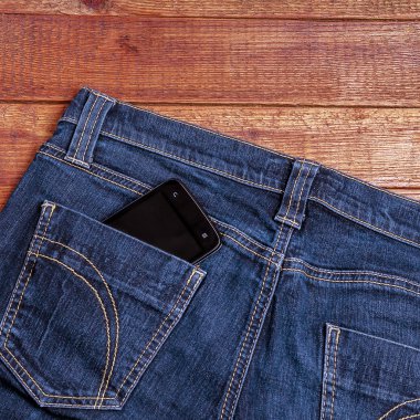 ahşap arka plan üzerinde eski kot pantolon cebinde Smartphone