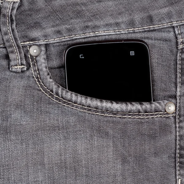 Smartphone en el viejo bolsillo vaquero sobre fondo de madera — Foto de Stock