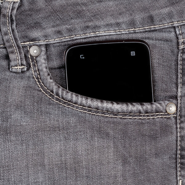 smartphone in the old jeans pocket on wood background