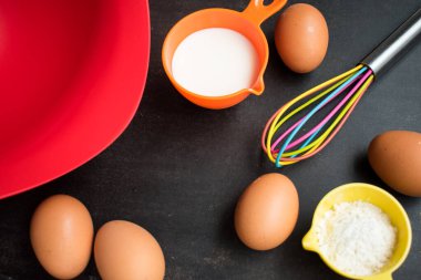 Siyah tahta bir masada kek pişirmek için yumurta, un ve süt. 