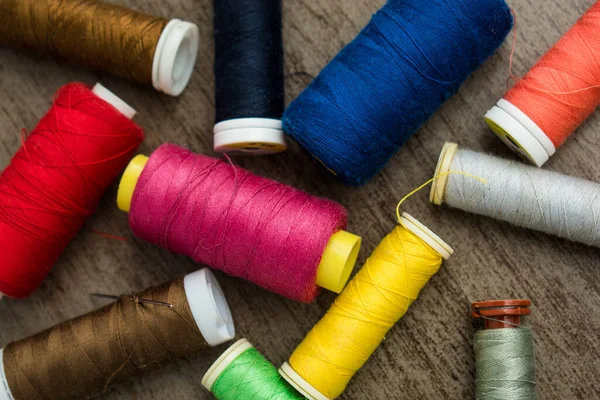Terzi dükkanındaki bir masanın üzerinde çok farklı renkte iplikler var.