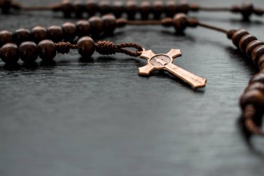 Tahta tespih ve metal haç siyah ahşap bir masada. 