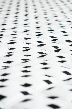 Düz bir çizgide siyah eşkenar dörtgenleri olan beyaz, büyük ve yumuşak yüzey.