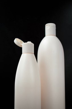 Siyah arka planı olan büyük beyaz şişeler. 