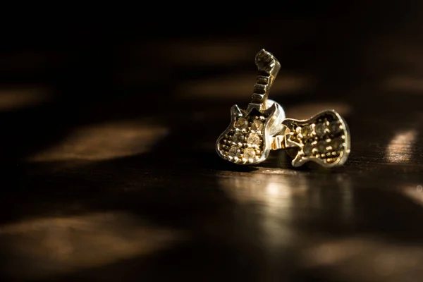 Siyah ahşap bir masanın üzerinde elmaslar olan gitar şeklinde bir mücevher. 