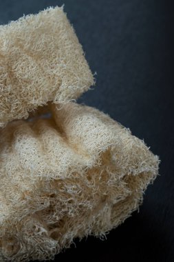 Siyah ahşap bir masada iki doğal beyaz sünger.