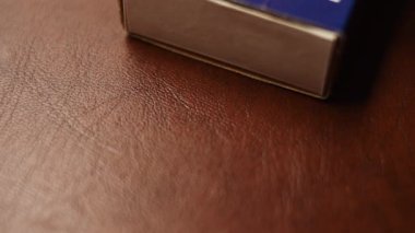 Tahta kibrit kutusundan bir kibrit alıp açarak.