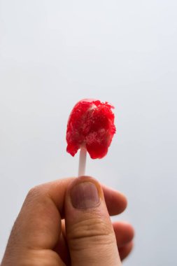 Beyaz arka planı olan kırmızı bir lolipopla el ele tutuşmak. 
