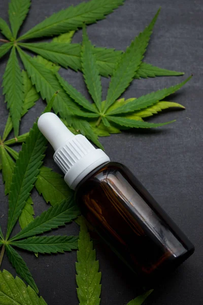 Üzerinde kenevir yaprakları olan cam kahve şişesi fotokopi alanı olan siyah ahşap bir masa. 