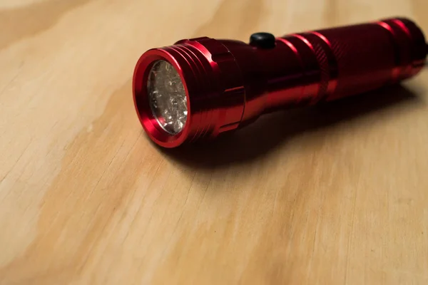 Fotokopi alanı olan ahşap bir masanın üzerinde kurşun ampulleri olan kırmızı parlak el feneri. 