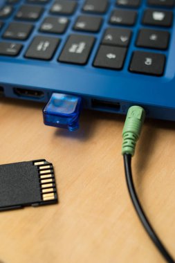 Kulaklık kabloları mavi modern bir dizüstü bilgisayara, USB belleğe ve SD belleğe bağlı. 