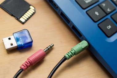 Kulaklık kabloları mavi modern bir dizüstü bilgisayara, USB belleğe ve SD belleğe bağlı. 