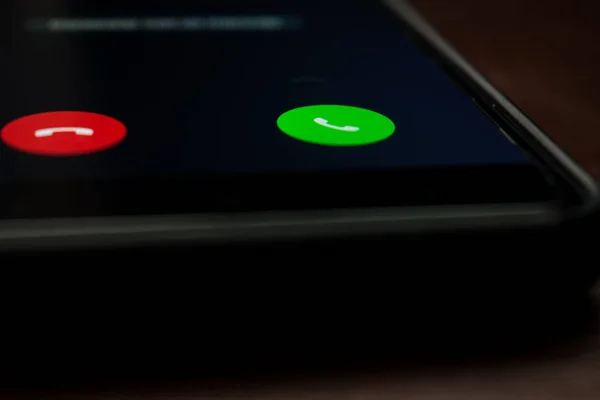 Siyah bir cep telefonuna, yeşil ve masanın üzerindeki bir düğmeyle yakın çekim yap. 