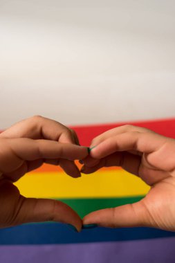 Renkli gökkuşağı bayrağı, arka plan olarak lgbt sembolü olan bir kalp yapmak için ellerinizi kapatın 