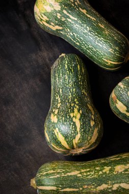 Siyah ahşap bir masada taze ve yeşil uzatılmış balkabağı.