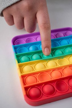 Beyaz bir masada, renkli bir çocuk oyuncağını iten parmak. 