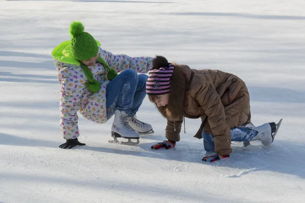 Two girls laughing rising after falling on ice — Stock Photo, Image