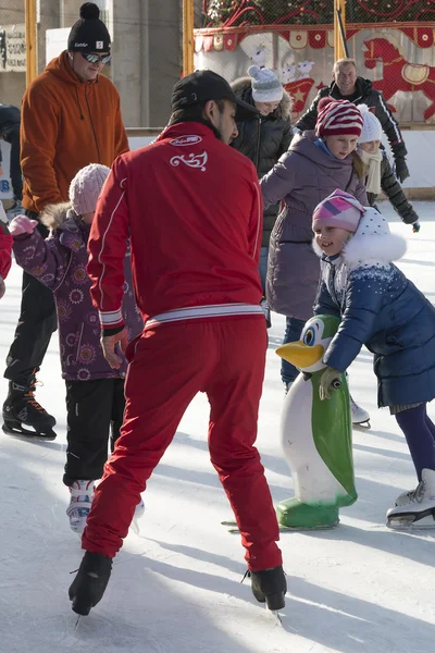 Entrenador en la pista de hielo enseña a los niños a patinar — Foto de Stock