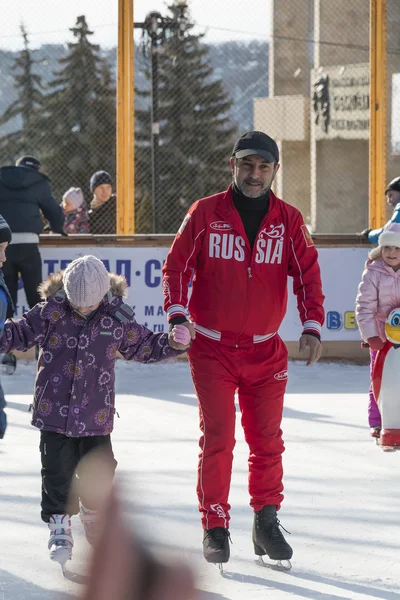 Entrenador en la pista de hielo enseña a los niños a patinar — Foto de Stock