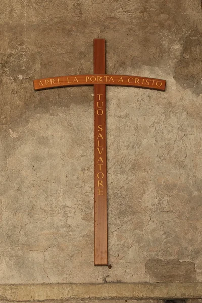 Cross on a old stucco wall with inscription on italian — Stock Photo, Image