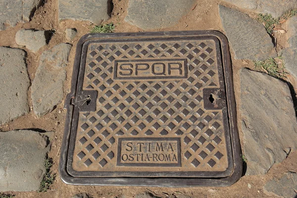 Rusty hatch with inscription on the street of Rome
