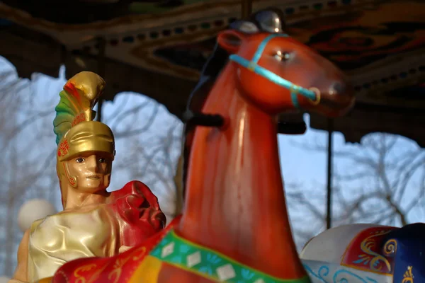 Gladiator in colorful carousel with horses — Stock Photo, Image