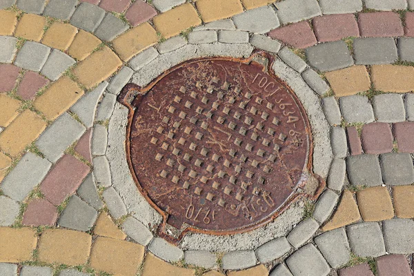Rusty metal manhole cover in a street — Stock Photo, Image