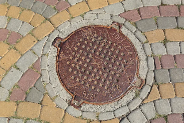 Rozsdás fém manhole fedezésére egy utcában — Stock Fotó