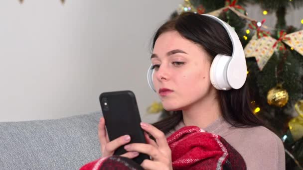 Vrouw tijdens kerstvakantie thuis blijven en muziek luisteren. Praat met iemand via de telefoon en lach. Praten met je vriendje — Stockvideo