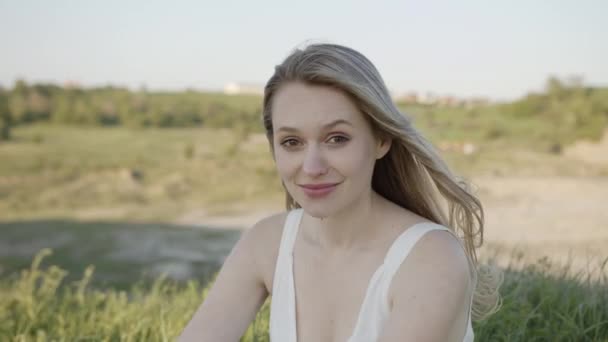 Glad blick av ung kvinna med chic leende som sitter på gräset — Stockvideo