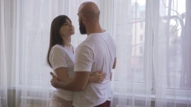 Pencerenin önünde birbirine aşık bir çiftin şefkatli bakışları ve öpücükleri.