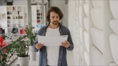 Bir adam, duvar kağıdı stüdyosunda bir inşaat projesini dikkatle inceliyor.