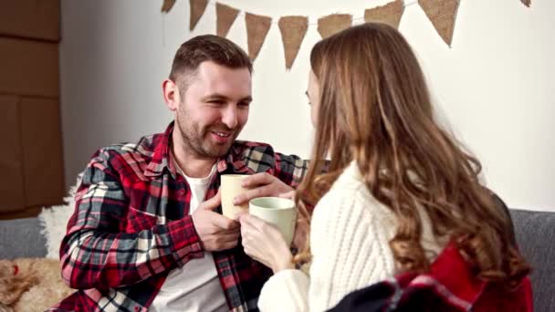 The newlyweds sit under a warm blanket and talk to each other over a cup of coffee — Stock Video