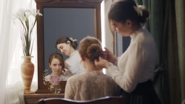 Chica ayuda a su hermana a desenredar su cabello. Su reflejo es visible en un espejo antiguo vintage — Vídeo de stock