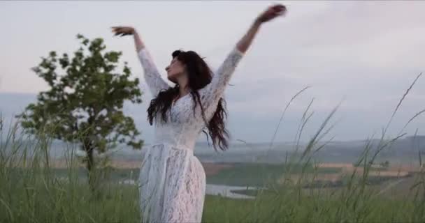 Κορίτσι με λευκό φόρεμα και σγουρές τρίχες χορεύει στο λιβάδι — Αρχείο Βίντεο